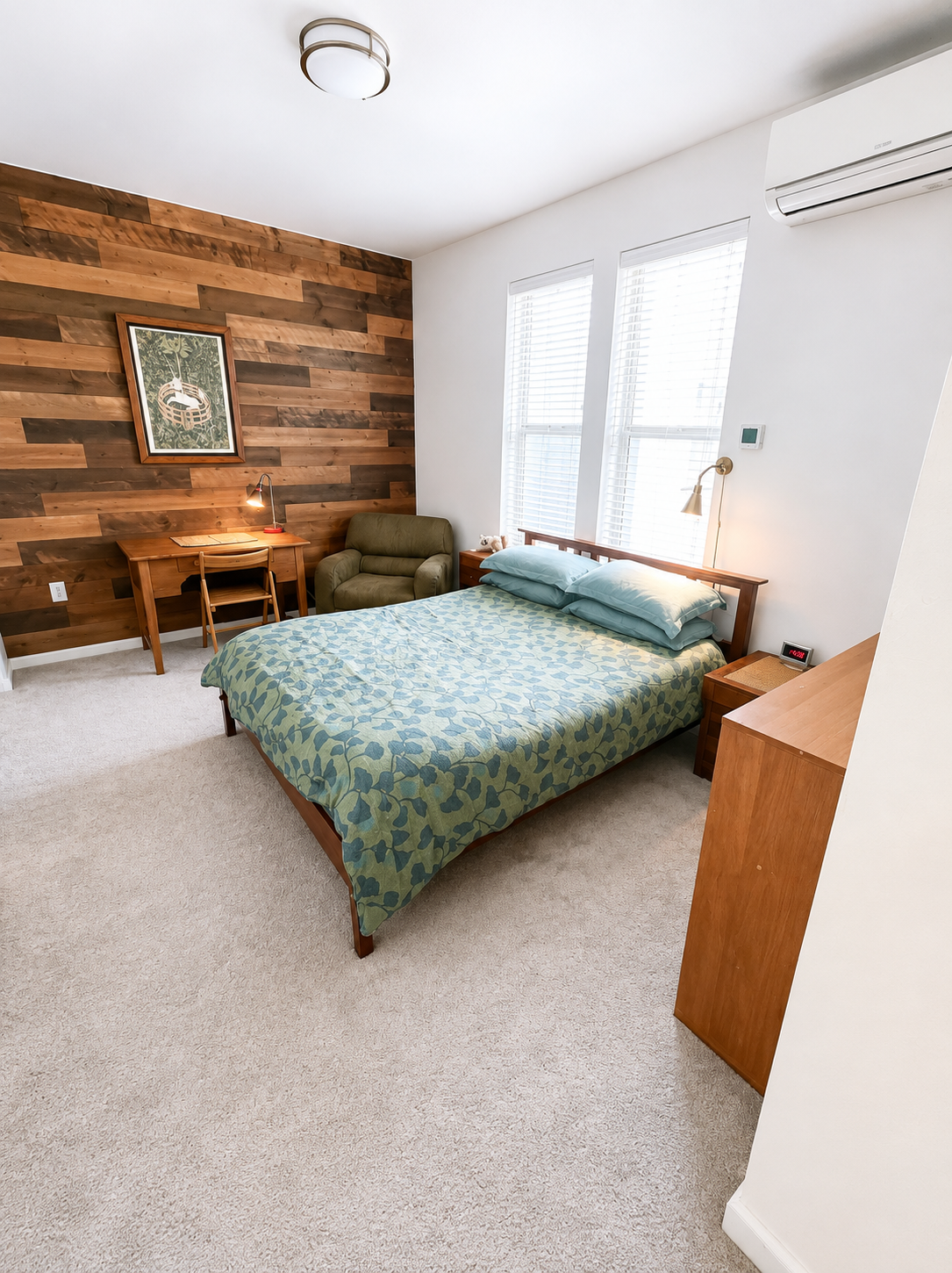 Furnished bedroom with wood accent wall and desk